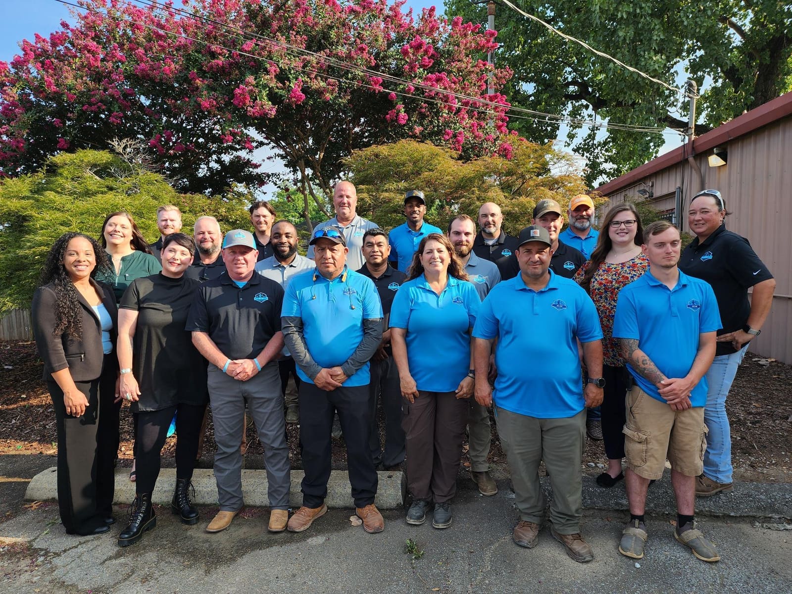 ALM team members outside the office under crape myrtles