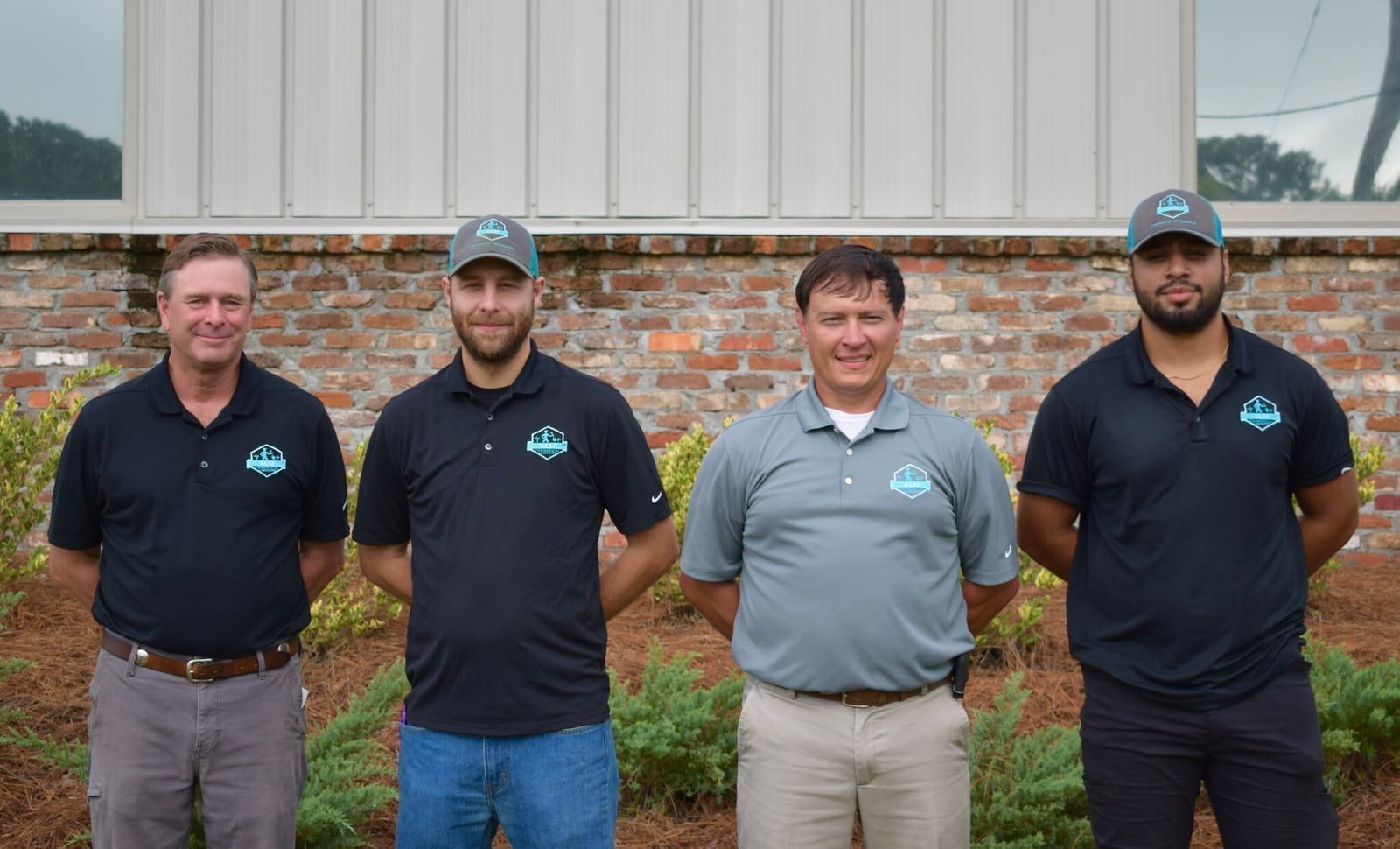 Four ALM team members in company shirts and caps